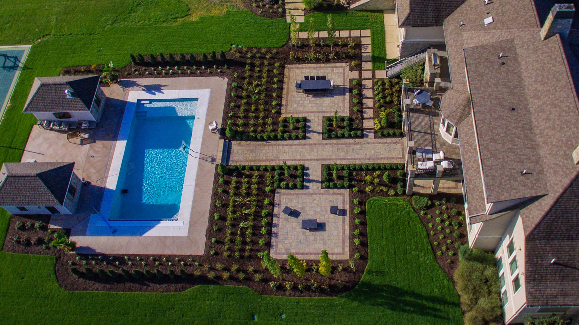 A bird's eye view of paved walkways and patio between a house and a pool in Okemos, MI.