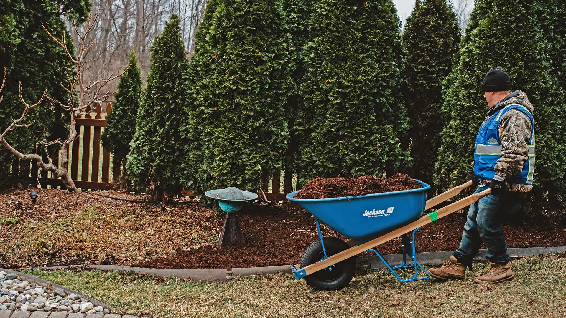 Our landscaper pushing a wheelbarrow full of mulch and soil by a home in Dewitt, MI.