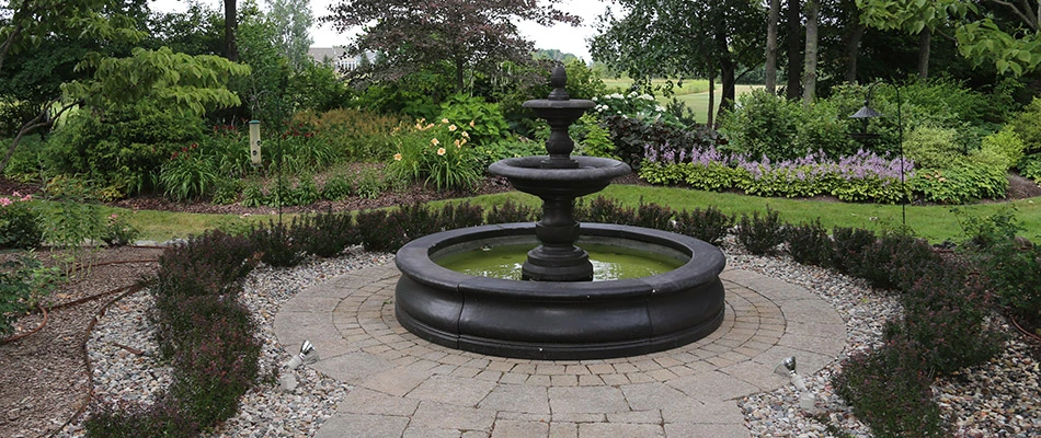 A tall black waterfall installed in the middle of a garden in Williamston, MI. 