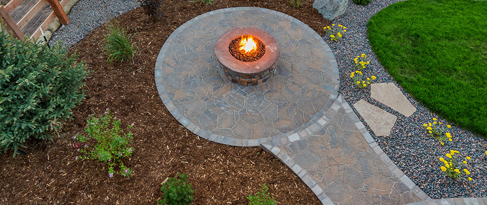 A freeform patio with a custom fire pit installed by a home in Okemos, MI.