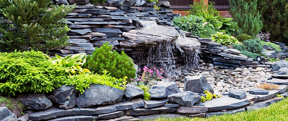 A pondless waterfall surrounded by stones and vegetation in Dewitt, MI.