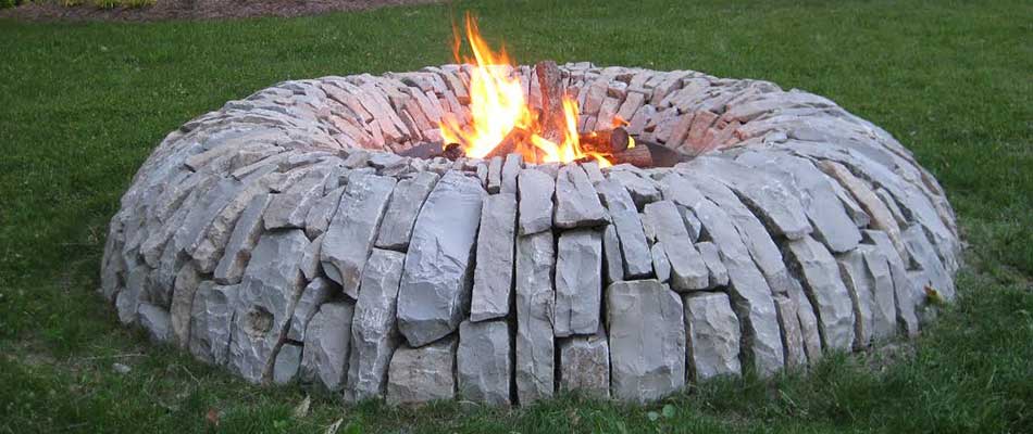 A custom stone fire pit installed in the backyard of a home in Dewitt, MI.