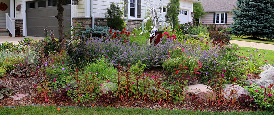 Landscape bed full of flowers and colorful bushes in front of a home in Dewitt, MI.