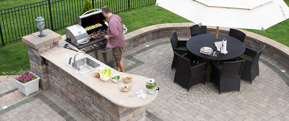 Custom outdoor kitchen with grill and sink on paver patio near East Lansing, MI.