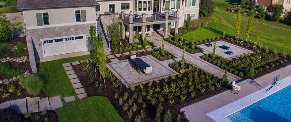 A home's backyard complete with paved walkways and patios and pool in Haslett, MI.