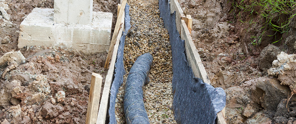 Rain conducter being installed underground at the base of a house to remove water from the foundation.