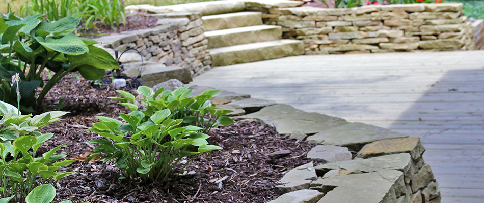 A retaining wall with landscape bed surrounding a patio in Lansing, MI.