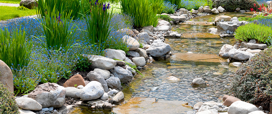 A stone stream surrounded by flowers and shrubs in Haslett, MI.