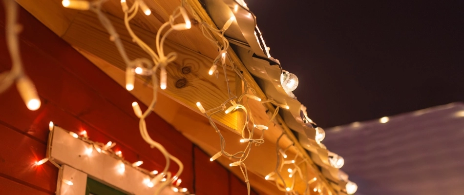 White holiday string lights installed around edge of roof top in Lansing, MI.